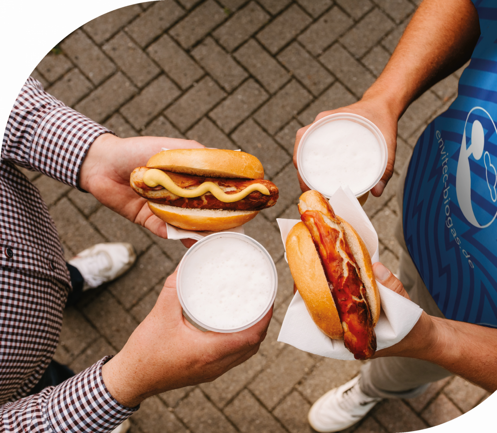 Bild Fußballfans mit Bier und Brauwurst im Brötchen in der Hand.
